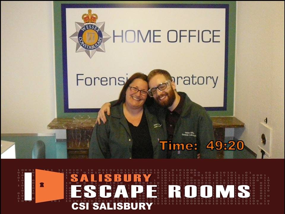 Anthony and Trenna pose after Corruption at the heart of WSCS at Salisbury Escape Rooms, in forensic jackets before a Wessex Constabulary laboratory sign.