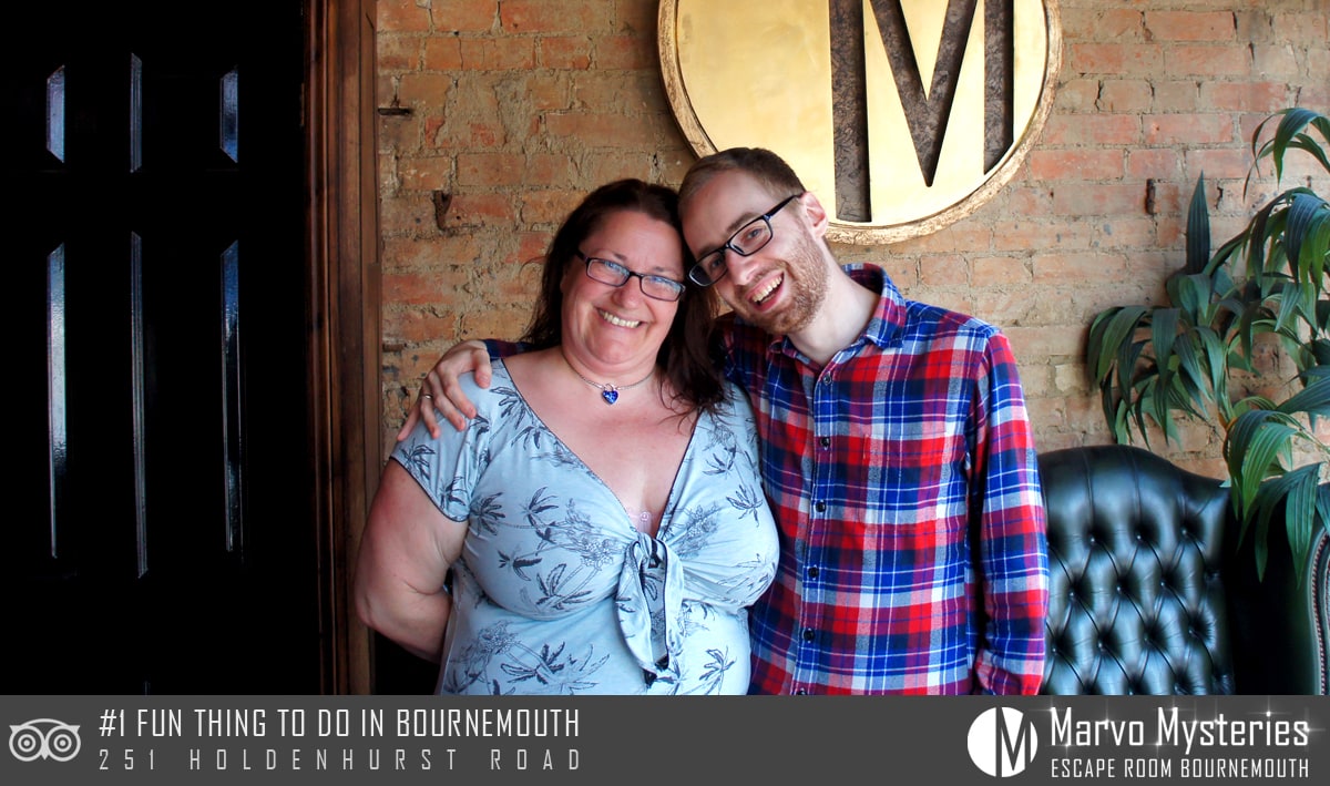 Anthony and Trenna pose after Room 1 MARVO Induction at Marvo Mysteries, before the brick Marvo Mysteries backdrop.