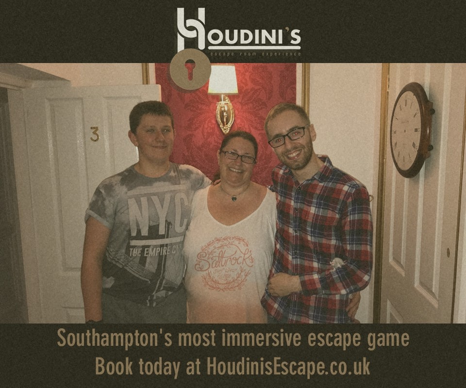 A three-person team pose after Titanic at Houdini, in a corridor beneath Houdini branding.