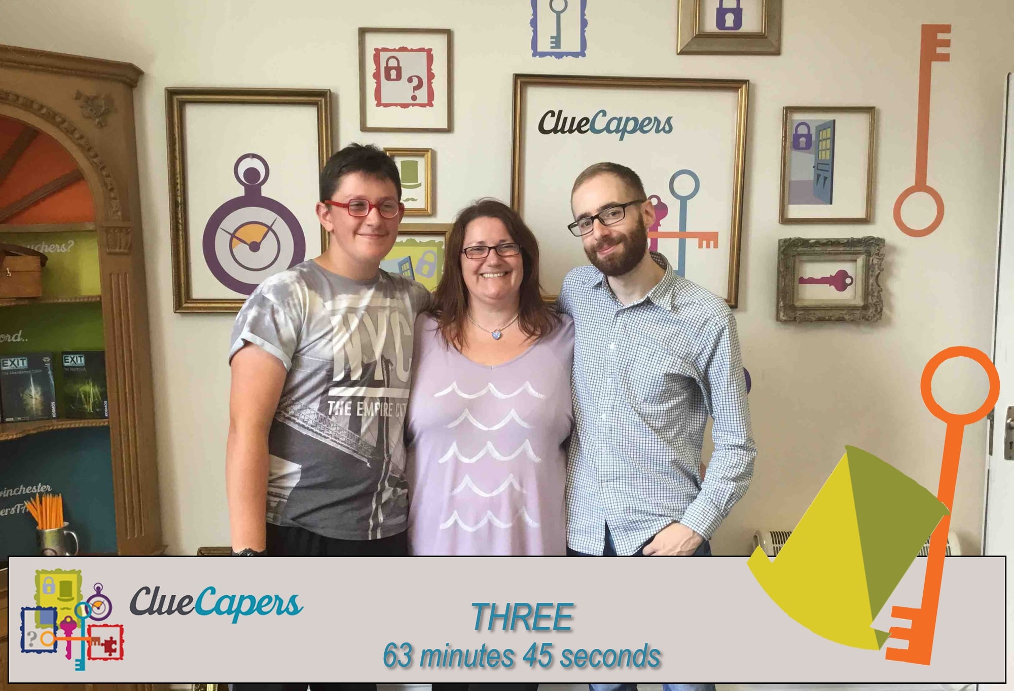 A three-person team pose after Misson to Winchintzy at ClueCapers, before a ClueCapers key-and-lock backdrop.