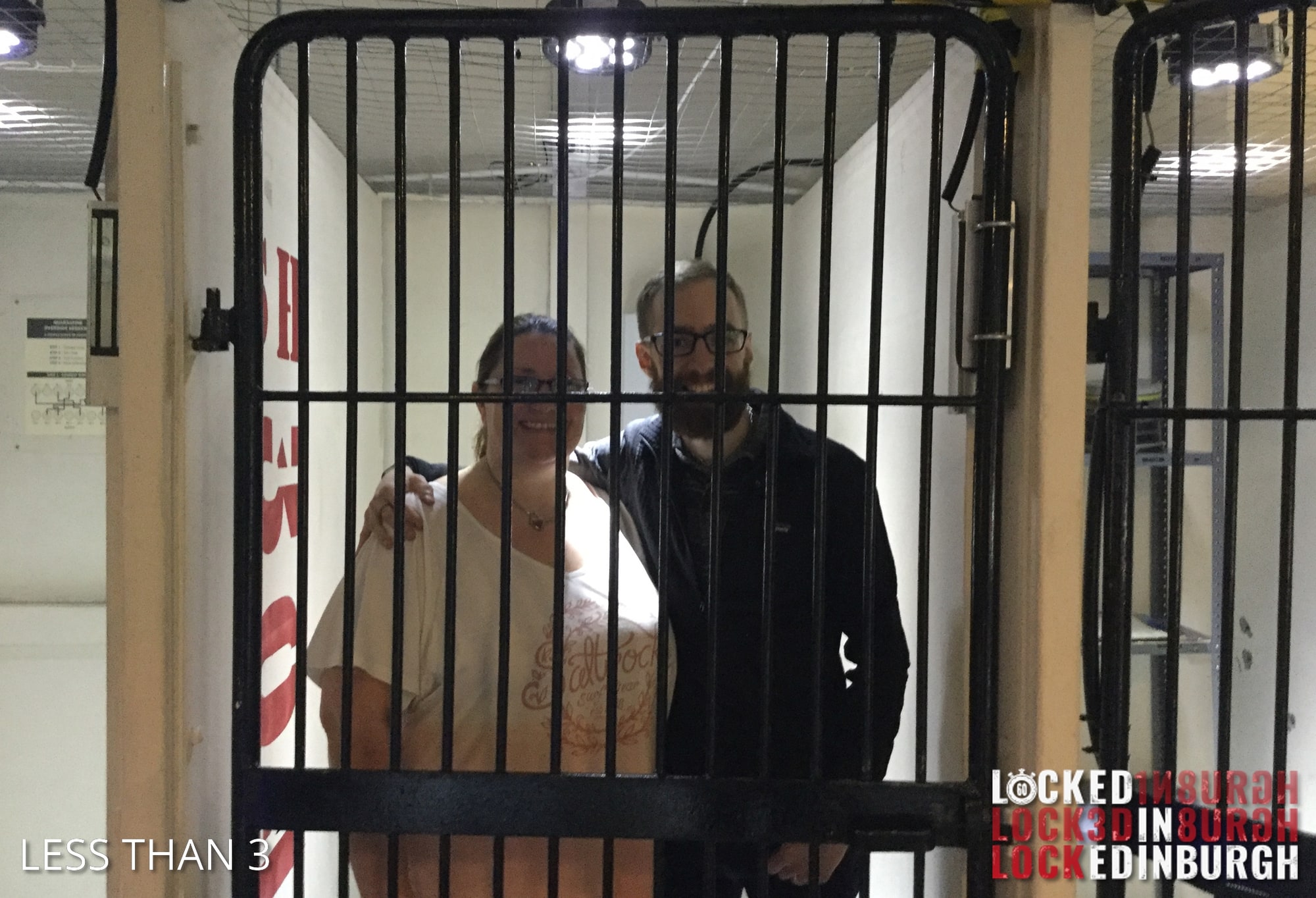 Anthony and Trenna pose after The Secret Lab at Locked in Edinburgh, behind black bars in a prison-themed setting.