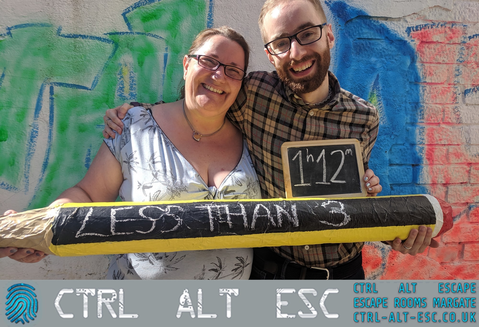 Anthony and Trenna pose after Detention at CTRL ALT ESC, with a time board and oversized pencil prop.
