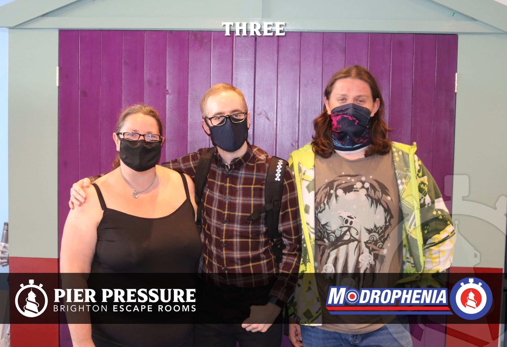 A three-person team pose after Modrophenia at Pier Pressure, before the purple Modrophenia door.