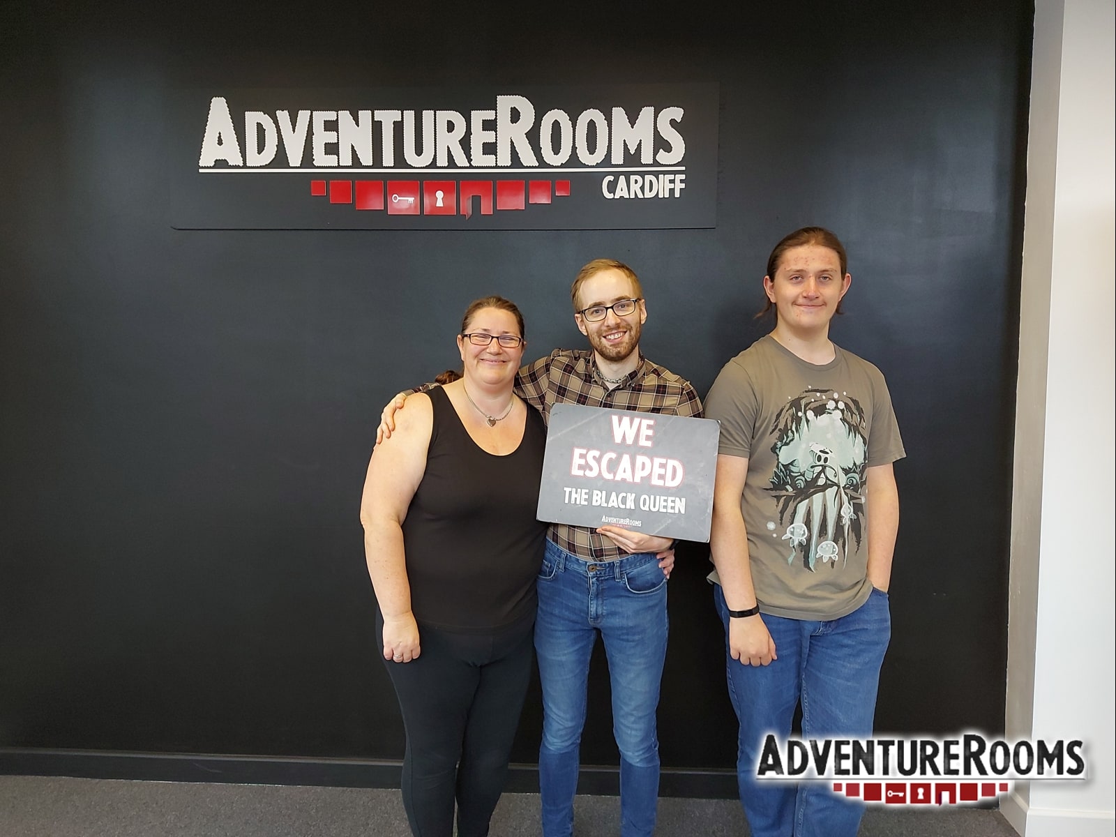 A three-person team pose after The Black Queen at Adventure Rooms, holding a We Escaped The Black Queen sign.