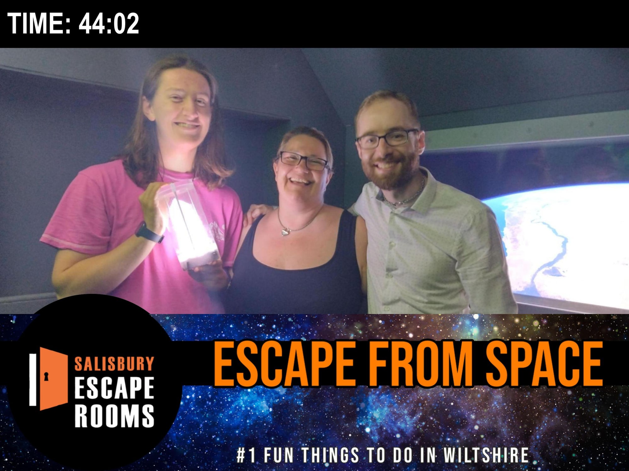 A three-person team pose after Escape from Space at Salisbury Escape Rooms, in the spacecraft-themed room with a glowing prop.