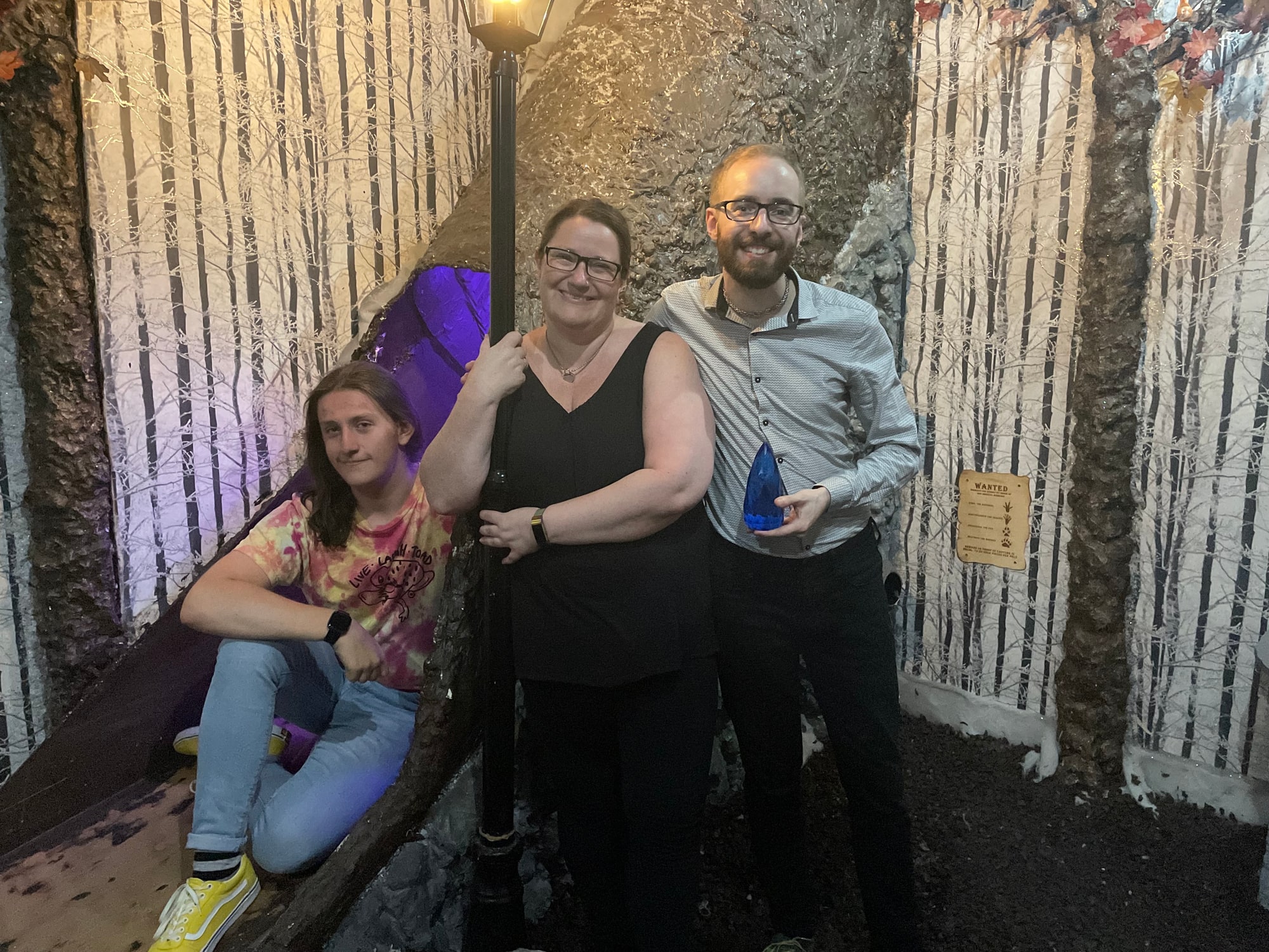 A three-person team pose after The enchanted forest at Breakescape, in the winter-forest room beside a lamppost.