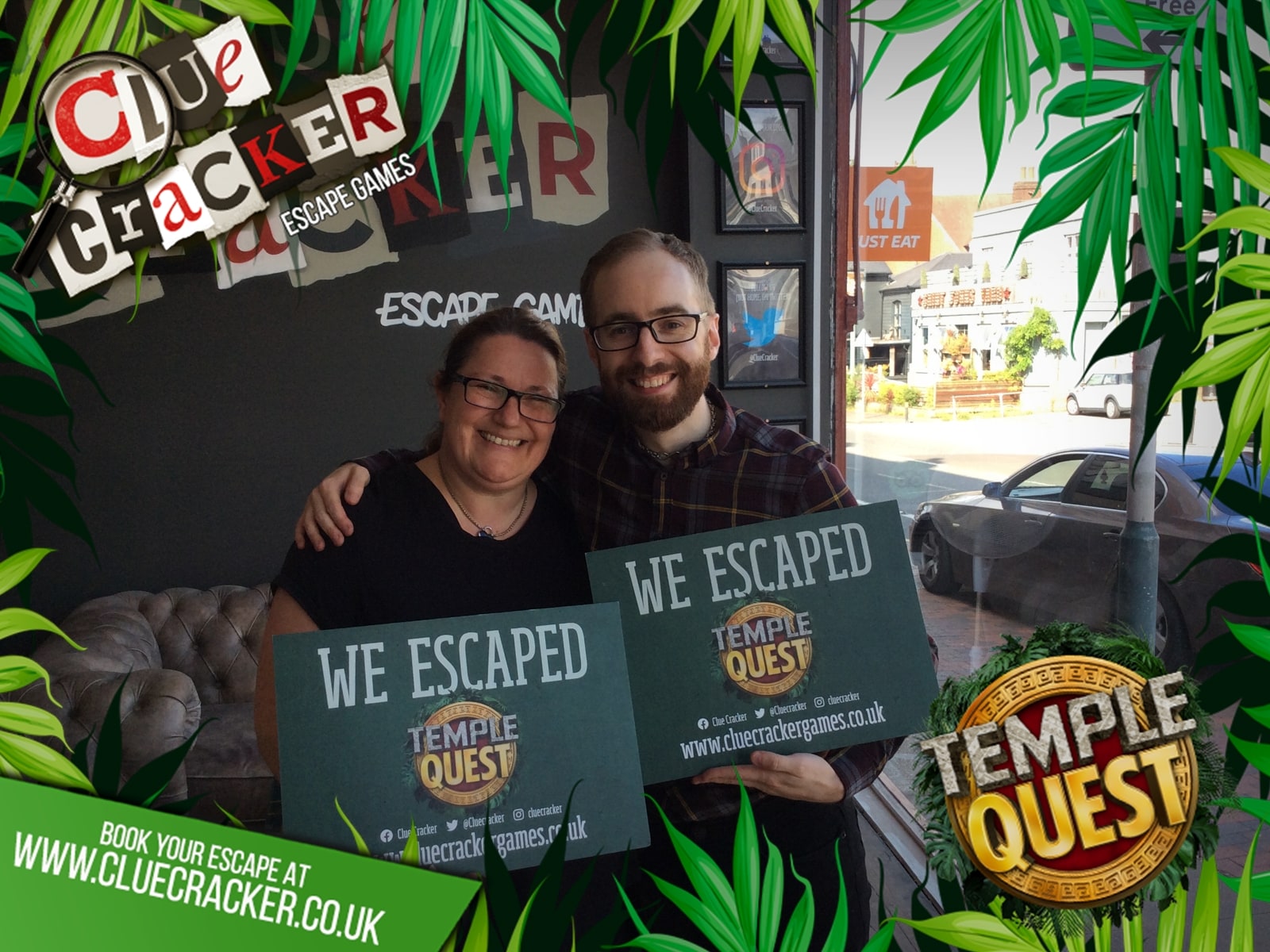 Anthony and Trenna pose after Temple quest at Clue Cracker, holding We Escaped Temple Quest signs.
