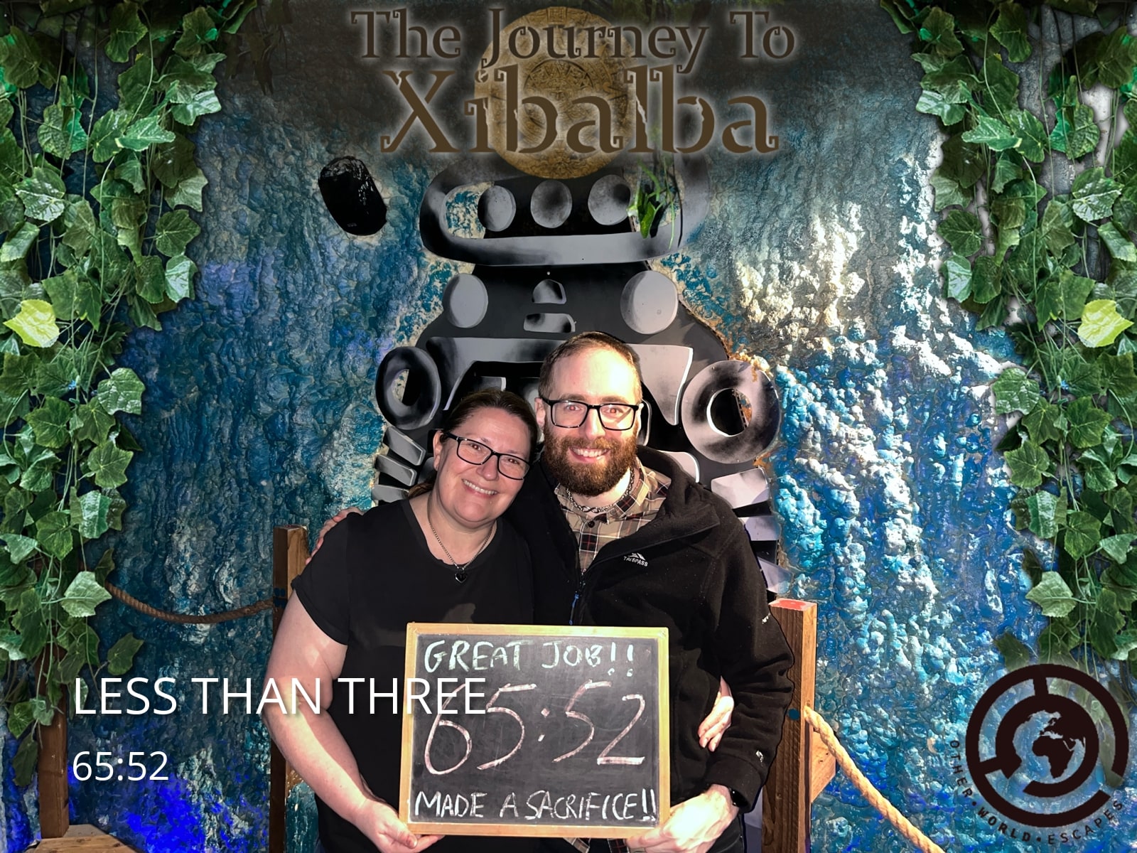 Anthony and Trenna pose after Xibalba at Other World Escapes, holding the Xibalba result sign before a cave-and-vines backdrop.