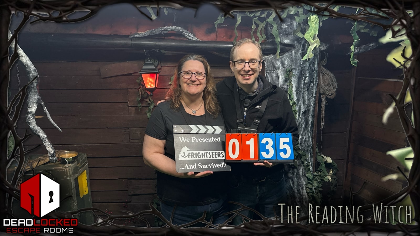 Anthony and Trenna pose after The Reading Witch at Deadlocked, holding Frightseers and 01:35 result boards in The Reading Witch set.