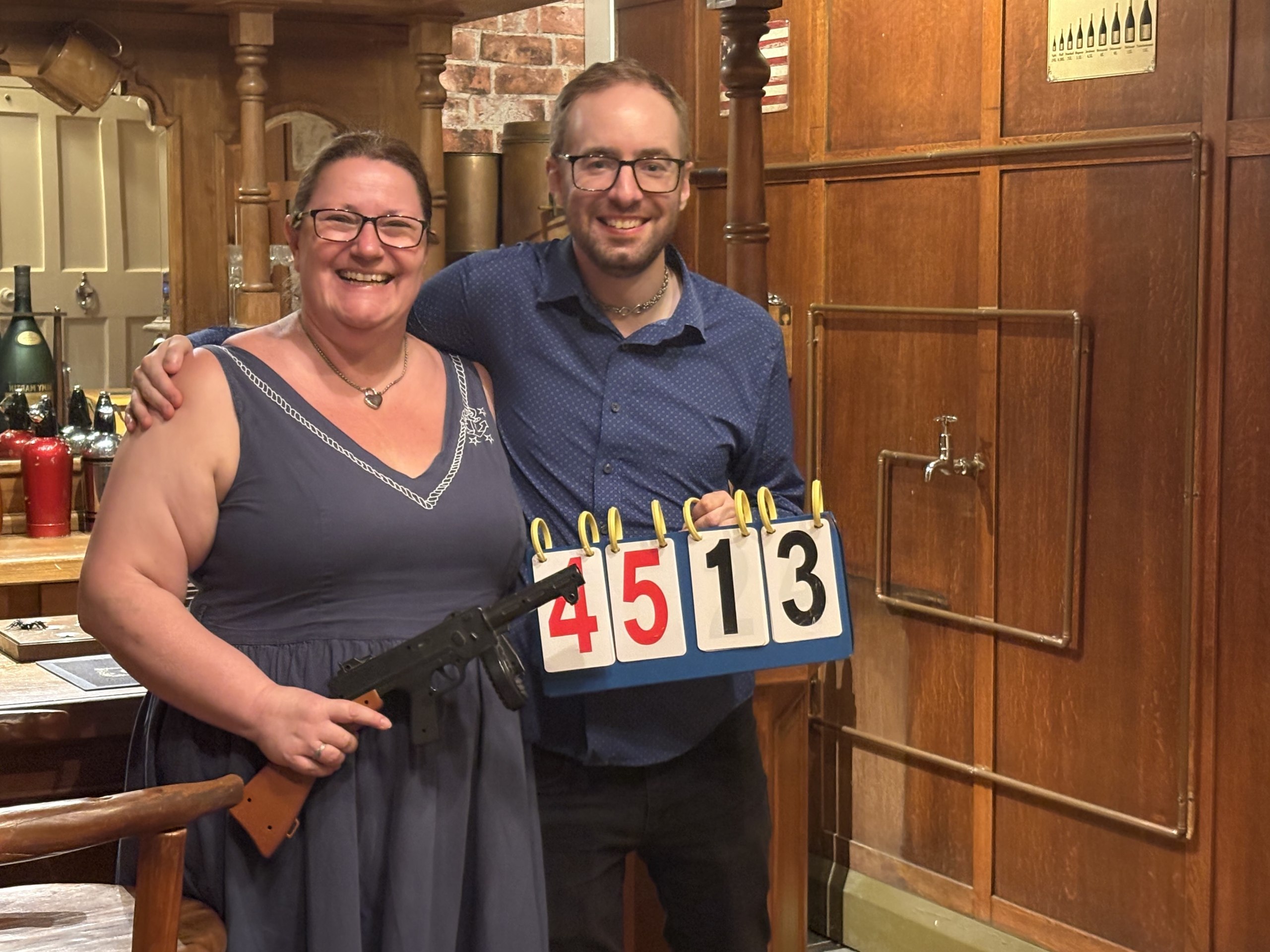 Anthony and Trenna smiling after completing Operation Moonshine at Escaporium, holding the 45:13 result board and saloon props.